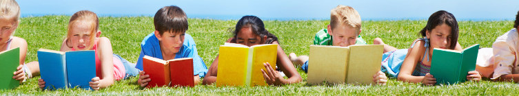 Children laying in grass reading books